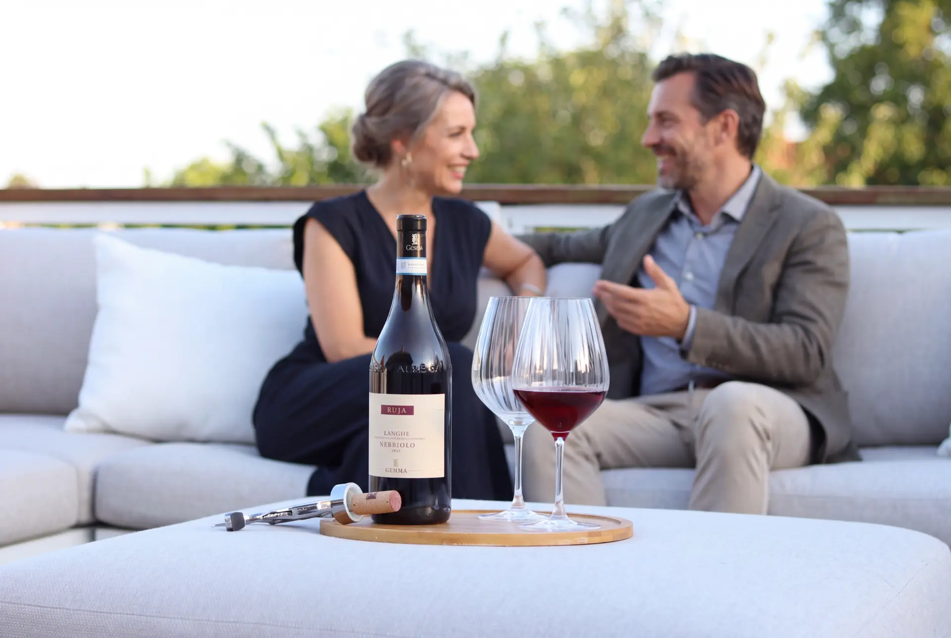To vinelskere deler en flaske Langhe Nebbiolo på en terrasse